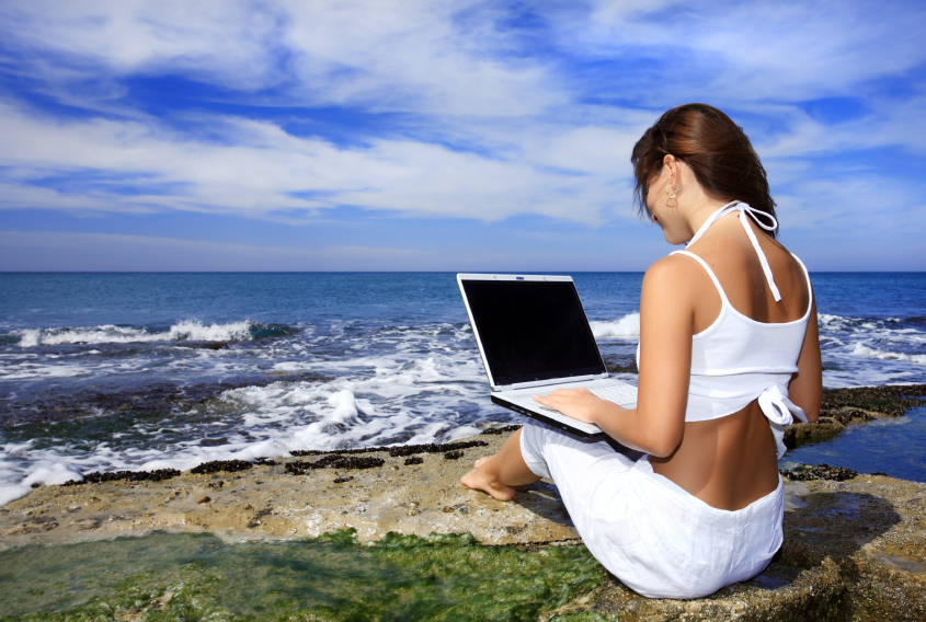 Girl with laptop computer on the beach.